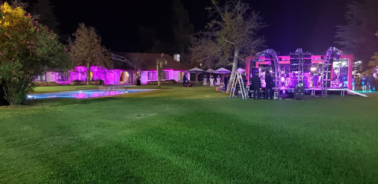 Producción nocturna en jardín con estructura de escenario y casa iluminada en Pirque